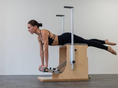 Beyaz kadın klasik sandalyede pilates yapıyor.