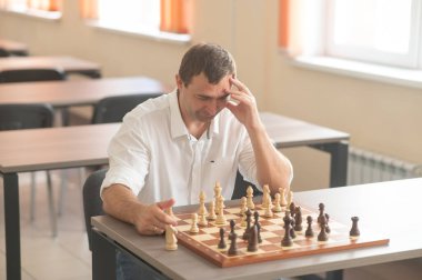 Beyaz adam satranç hamlesi düşünüyor.