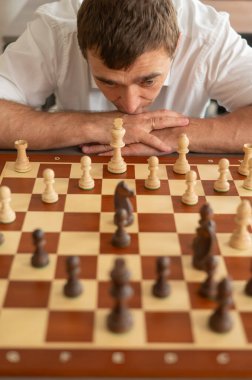 Beyaz adam satranç hamlesi düşünüyor.