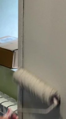 Kafkas kadın silindirle duvar boyuyor.