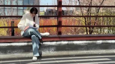 Açık havada kalemle çizim yapan beyaz bir kadın.