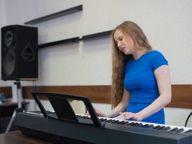 Beyaz kadın elektrikli piyano çalıyor.