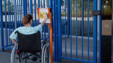 Tekerlekli sandalyedeki bir kadın dokunmaya duyarlı körler için yardım düğmesi kullanır..