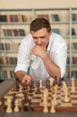 Beyaz adam satranç hamlesi düşünüyor.