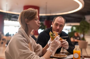 Beyaz bir çift hamburger yiyor.