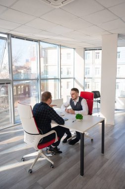 İki beyaz adam bir iş toplantısında iletişim kuruyor.