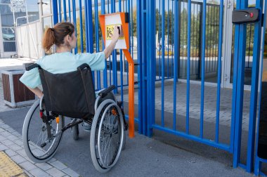 Tekerlekli sandalyedeki bir kadın dokunmaya duyarlı körler için yardım düğmesi kullanır..
