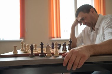 Beyaz adam satranç hamlesi düşünüyor.