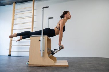 Beyaz kadın klasik sandalyede pilates yapıyor.