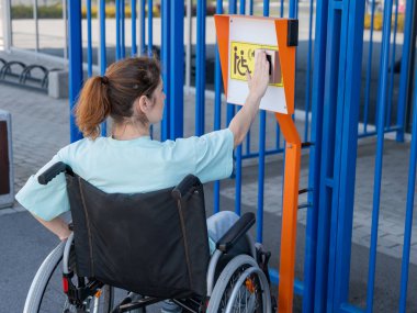Tekerlekli sandalyedeki bir kadın dokunmaya duyarlı körler için yardım düğmesi kullanır..