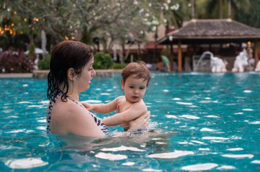 Beyaz kadın tatilde havuzda yüzerken oğlunu kucağına aldı