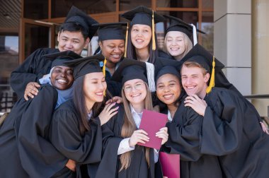 Farklı uluslardan mutlu öğrenciler mezuniyet elbiseleriyle diplomalarını tutuyorlar.