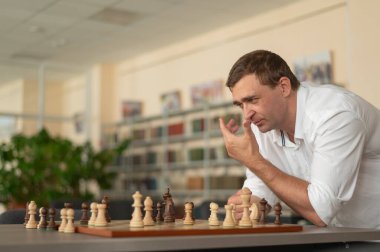 Beyaz adam satranç hamlesi düşünüyor.