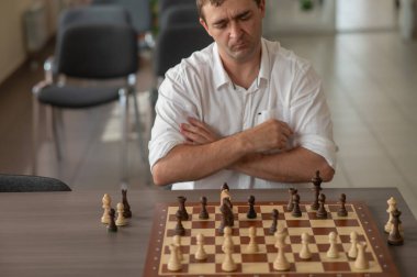 Beyaz adam satranç hamlesi düşünüyor.