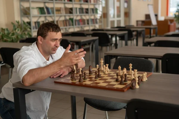 Beyaz adam satranç hamlesi düşünüyor.