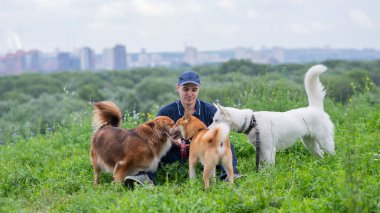 Beyaz bir adam üç köpekle yürür. Köpek gezdirici