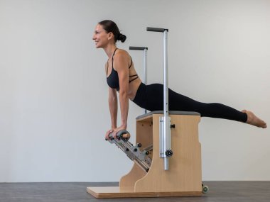 Beyaz kadın klasik sandalyede pilates yapıyor.