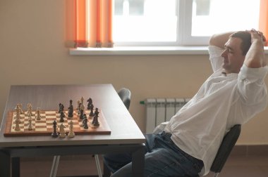 Beyaz adam satranç hamlesi düşünüyor.