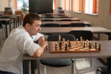 Beyaz adam satranç hamlesi düşünüyor.