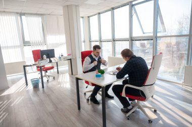 İki beyaz adam bir iş toplantısında iletişim kuruyor.