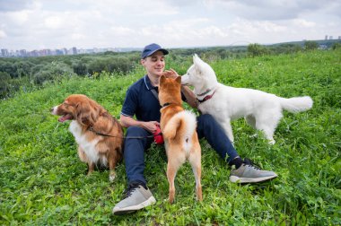 Beyaz bir adam üç köpekle yürür. Köpek gezdirici