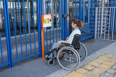 Tekerlekli sandalyedeki bir kadın dokunmaya duyarlı körler için yardım düğmesi kullanır..