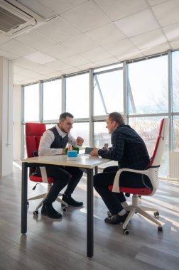 İki beyaz adam bir iş toplantısında iletişim kuruyor.