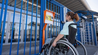 Tekerlekli sandalyedeki bir kadın dokunmaya duyarlı körler için yardım düğmesi kullanır..