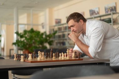 Beyaz adam satranç hamlesi düşünüyor.