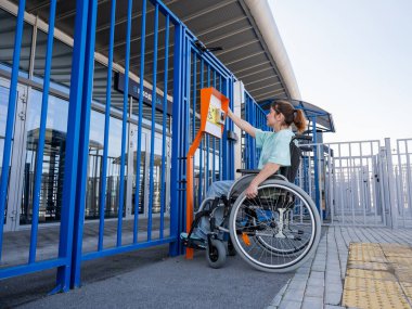 Tekerlekli sandalyedeki bir kadın dokunmaya duyarlı körler için yardım düğmesi kullanır..