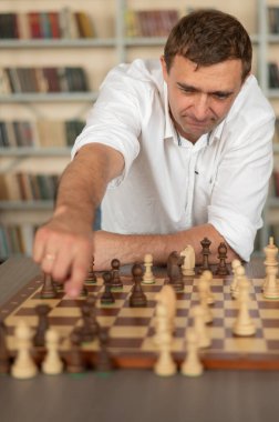 Beyaz adam satranç hamlesi düşünüyor.