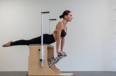 Beyaz kadın klasik sandalyede pilates yapıyor.