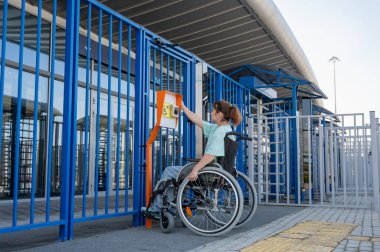 Tekerlekli sandalyedeki bir kadın dokunmaya duyarlı körler için yardım düğmesi kullanır..