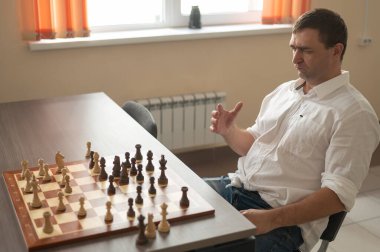 Beyaz adam satranç hamlesi düşünüyor.