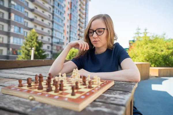 Beyaz kadın dışarıda satranç oynuyor.