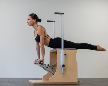 Beyaz kadın klasik sandalyede pilates yapıyor.