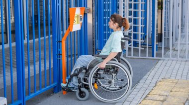 Tekerlekli sandalyedeki bir kadın dokunmaya duyarlı körler için yardım düğmesi kullanır..