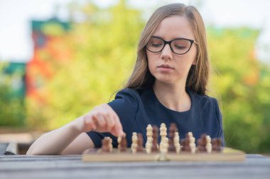 Beyaz kadın dışarıda satranç oynuyor.