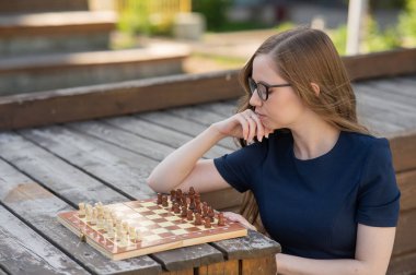 Beyaz kadın dışarıda satranç oynuyor.