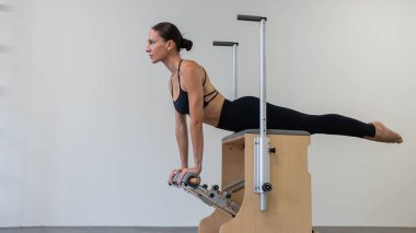 Beyaz kadın klasik sandalyede pilates yapıyor.
