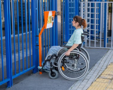 Tekerlekli sandalyedeki bir kadın dokunmaya duyarlı körler için yardım düğmesi kullanır..