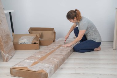 Beyaz bir kadın bir kutu mobilyayı açıyor.