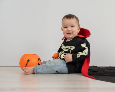 Beyaz arka planda şeker sepeti tutan Dracula Cadılar Bayramı kostümlü beyaz tatlı çocuk.