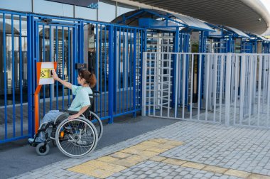 Tekerlekli sandalyedeki bir kadın dokunmaya duyarlı körler için yardım düğmesi kullanır..