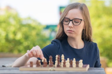 Beyaz kadın dışarıda satranç oynuyor.