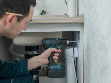 Teknisyen mutfak dolabındaki kapıyı açar.