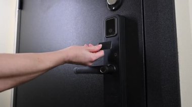 Bir kadın, erişimi olmayan bir anahtarla modern bir kapı kilidini açar.