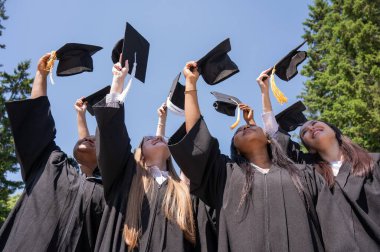 Farklı milletlerden genç kadınlar mezuniyet şapkalarını takıyorlar.