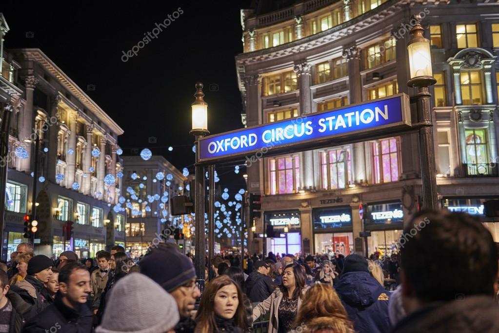 LONDON, UK - DECEMBER 20: Nighttime shot of very crowded Oxford Circus underground entrance with Christmas lights in the background. December 20, 2014 in London.