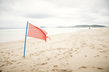 Uyarı işareti bulutlu bir sk ile güzel bir plajda bir kırmızı bayrağı